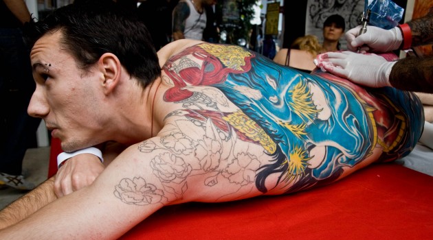 A man receives a colorful tattoo at a tattoo art fest in Paris (Flickr photo by Philleppe Leroyer)